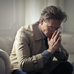 A sad Man with financial stress sitting in his living room.